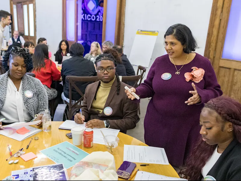 Four participants seated around a table in discussion during a workshop on instant payment systems and financial inclusion.